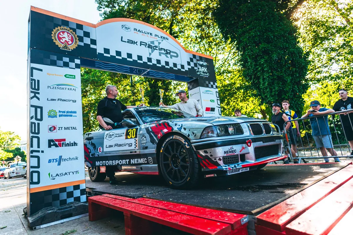 Vít Němec a spolujezdec s poháry na cílové rampě Rallye Plzeň 2026 u BMW M3 E36